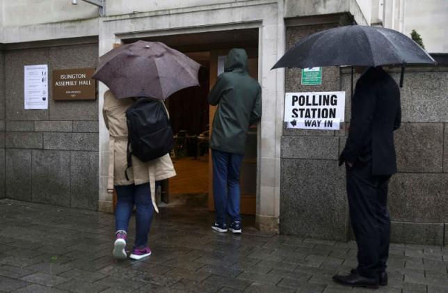 People queue in the rain outside a polling station for the Referendum on the European Union in north London, Britain