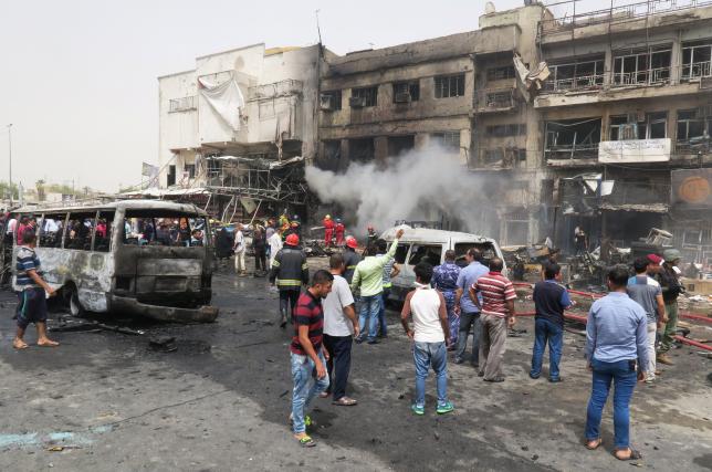 People gather at the site of car bomb attack in Baghdad al-Jadeeda