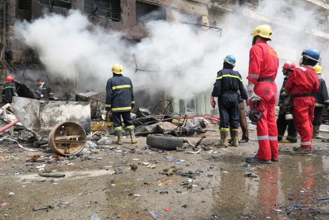 Firemen look at smoke from a burning building at the site of a car bomb attack in Baghdad al-Jadeeda