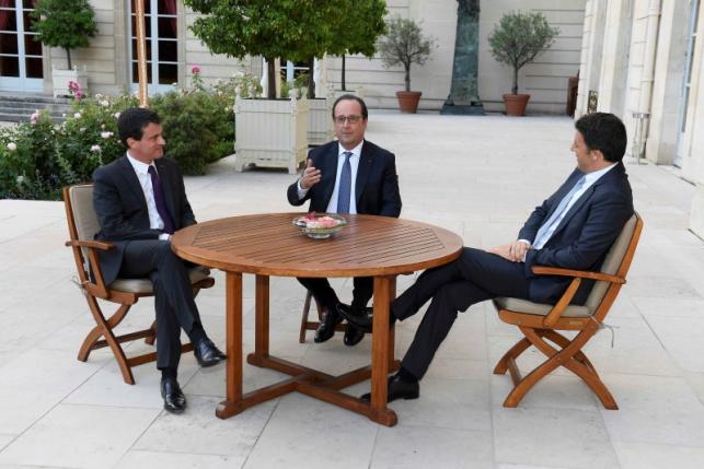 French Prime Minister Manuel Valls, French President Francois Hollande and Italy's Prime Minister Matteo Renzi sit at a table overlooking the garden at the Elysee Palace in Paris