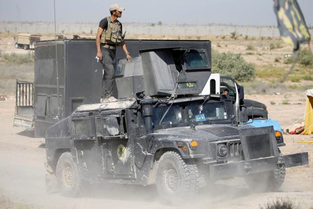 A member of the Iraqi security forces ride atop a military vehicle near Falluja