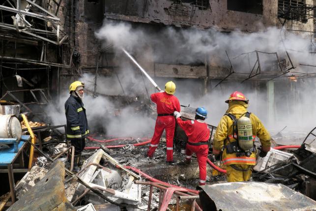 Firemen hose down a burning building at the site of car bomb attack in Baghdad al-Jadeeda