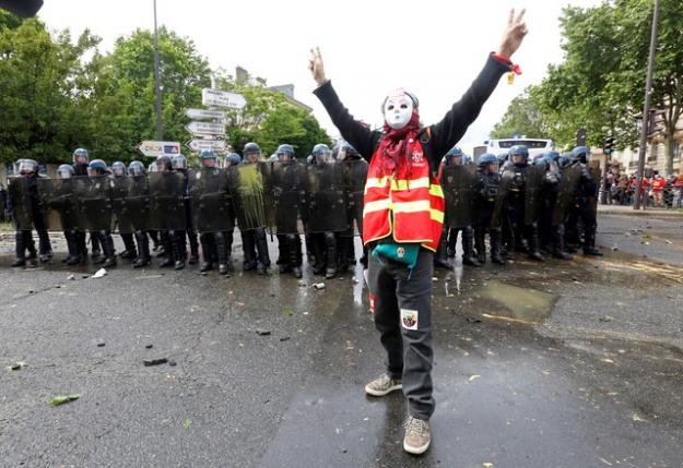A masked youth faces off with French riot police during a demonstration in Paris as part of nationwide protests against plans to reform French labour laws