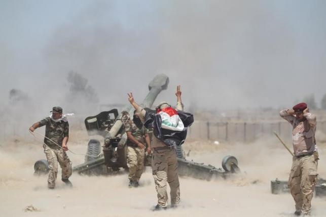 Shi'ite fighters and Iraqi security forces fire artillery during clashes with Islamic State militants near Falluja