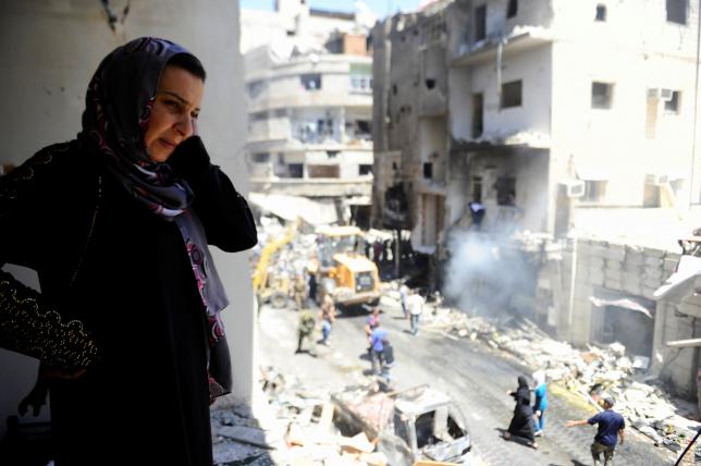 A woman inspects a damaged site after a suicide and car bomb attack in south Damascus Shi'ite suburb of Sayeda Zeinab
