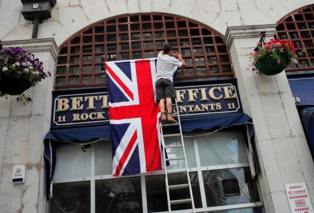 A worker places the Union Jack flag on the facade of a shop at Casesmates square where Cameron will attend a 'Stronger In' campaign event in the British overseas territory Gibraltar, historically claimed by Spain