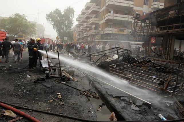 Firemen hose down a burning building as civilians gather after a suicide car bomb occurred in the Karrada shopping area in Baghdad, Iraq