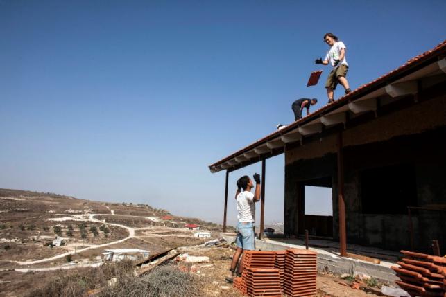Men work on the roof of a house under construction in the unauthorised Jewish settler outpost of Havat Gilad, south of the West Bank city of Nablus